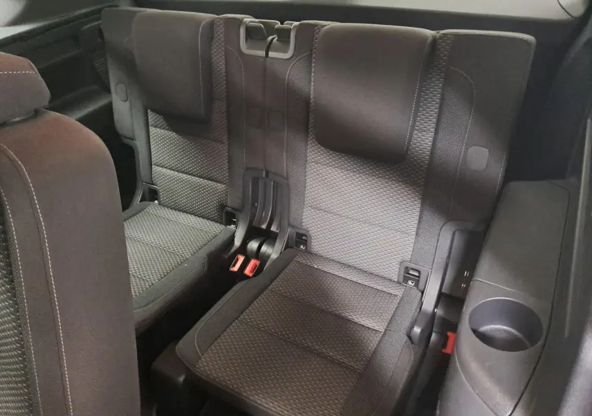Vue rapprochée des sièges arrière en tissu gris foncé du Volkswagen Touran 2024, troisième rangée avec porte-gobelet intégré.