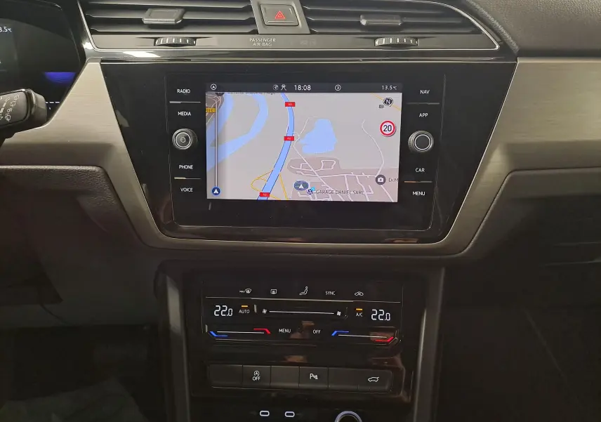 Vue rapprochée de la console centrale du Volkswagen Touran 2024, écran tactile avec navigation et commandes climatisation digitales.