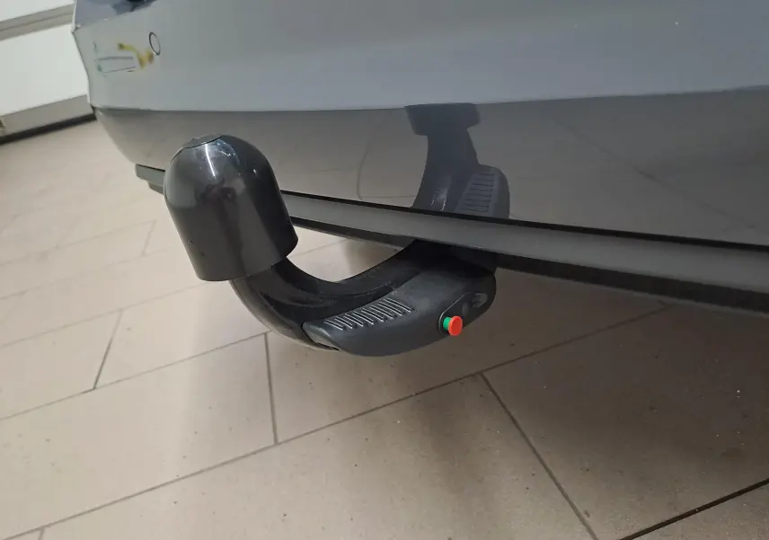 Gros plan sur l'attelage démontable noir sous le pare-chocs arrière du Volkswagen Touran gris Dauphin 2024.