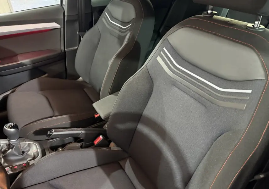 Vue rapprochée des sièges avant noirs avec surpiqûres rouges et motifs gris dans l’habitacle d’une SEAT Ibiza 2024.