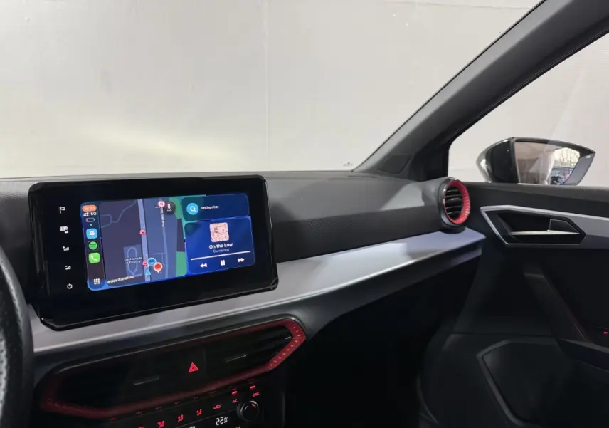 Vue intérieure côté passager de la SEAT Ibiza gris foncé 2024, avec écran tactile central et aérateurs rouges.