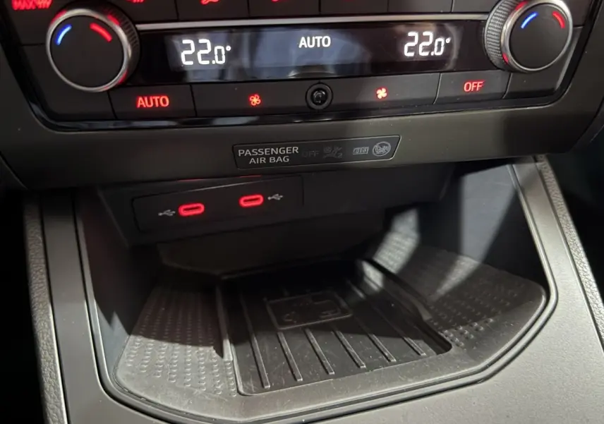 Gros plan sur la console centrale de la SEAT Ibiza 2024 gris foncé, montrant la climatisation digitale et deux ports USB rouges.