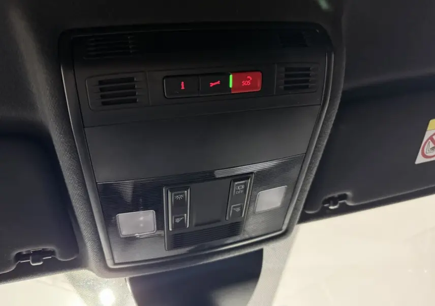 Vue en contre-plongée du panneau de commandes au plafond intérieur de la SEAT IBIZA gris foncé, avec bouton SOS éclairé en rouge.