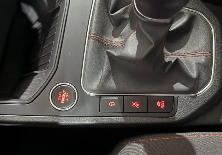 Gros plan sur la console centrale de la SEAT IBIZA 1.0 TSI 110 FR 2024 avec levier de vitesses et boutons lumineux rouges.