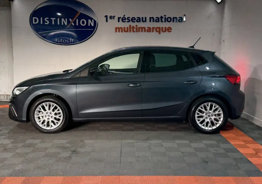 Profil droit d'une SEAT Ibiza gris foncé 2024 garée en intérieur avec jantes alliage et feux arrière allumés.