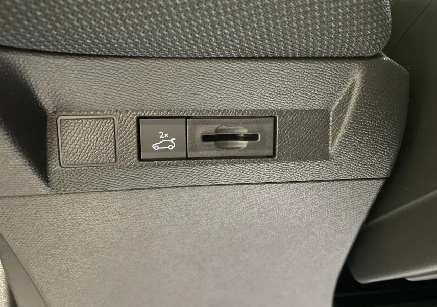 Détail du bouton d'ouverture du hayon électrique sur la planche de bord noire du Citroën C5 Aircross Bleu Azul.