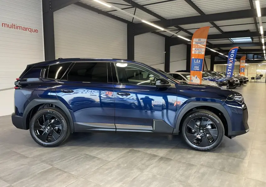 Vue latérale gauche d'un Citroën C5 Aircross bleu Azul avec jantes alliage noires en showroom.