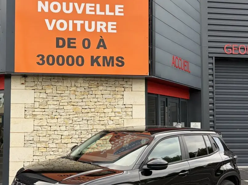 Jeep Avenger noir vue 3/4 avant droit, SUV compact avec calandre distinctive et jantes modernes, devant un bâtiment commercial.