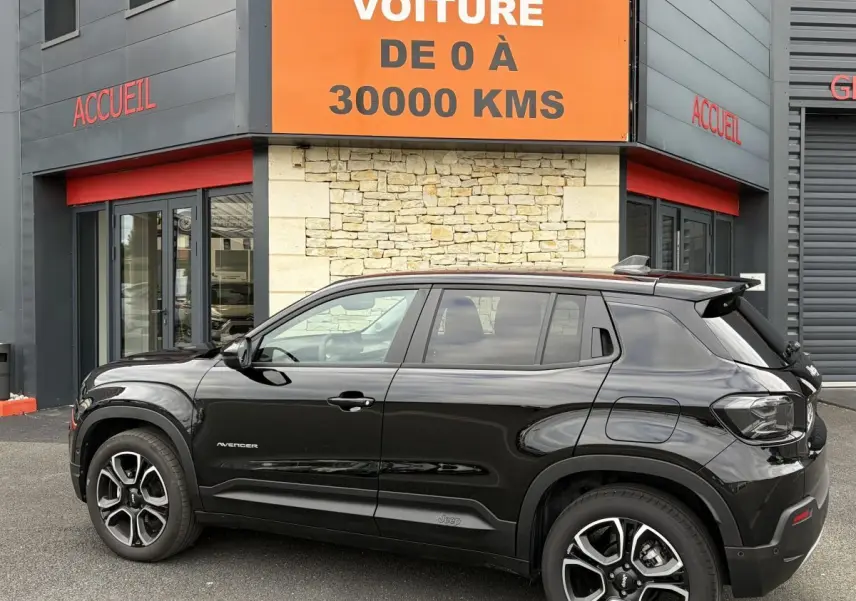 Vue latérale droite d'un Jeep Avenger noir 2025 garé devant un bâtiment avec panneau orange "Votre nouvelle voiture".