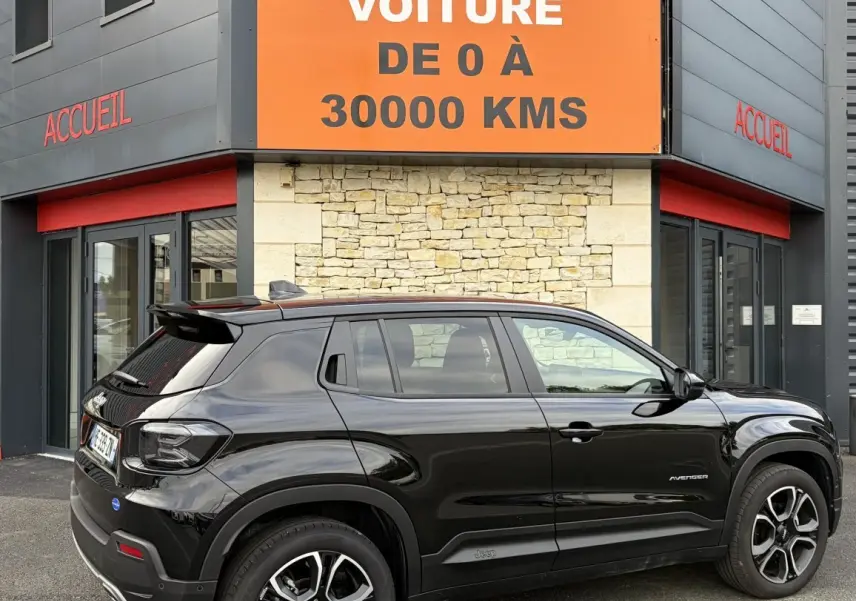 Jeep Avenger noir en vue de profil côté droit, garé devant un bâtiment avec panneau orange "Votre nouvelle voiture".