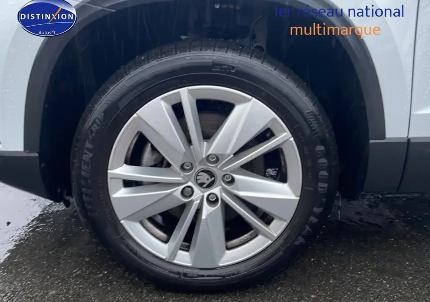 Gros plan sur la roue avant droite avec jante alu du Skoda Karoq blanc glacial 2025.