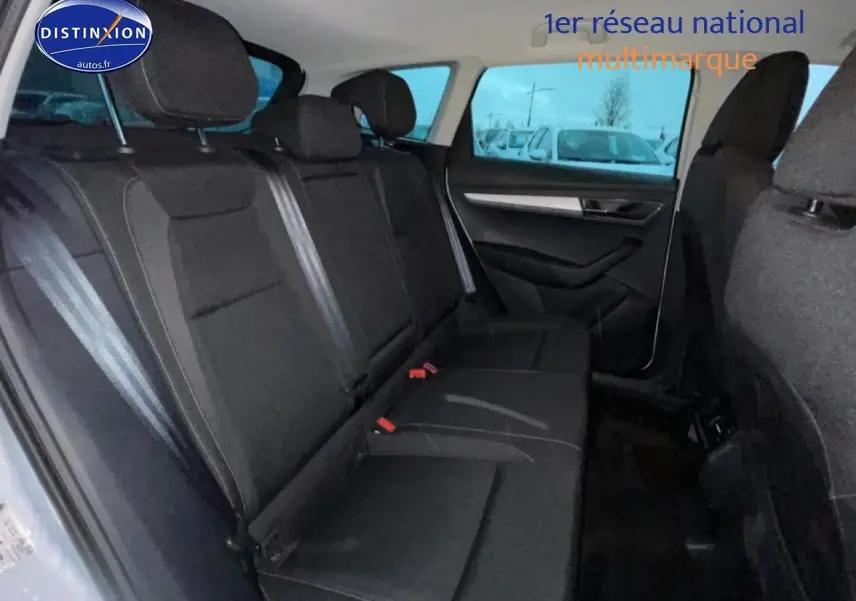 Vue intérieure arrière côté droit du Skoda Karoq blanc glacial, montrant la banquette noire et les ceintures de sécurité.