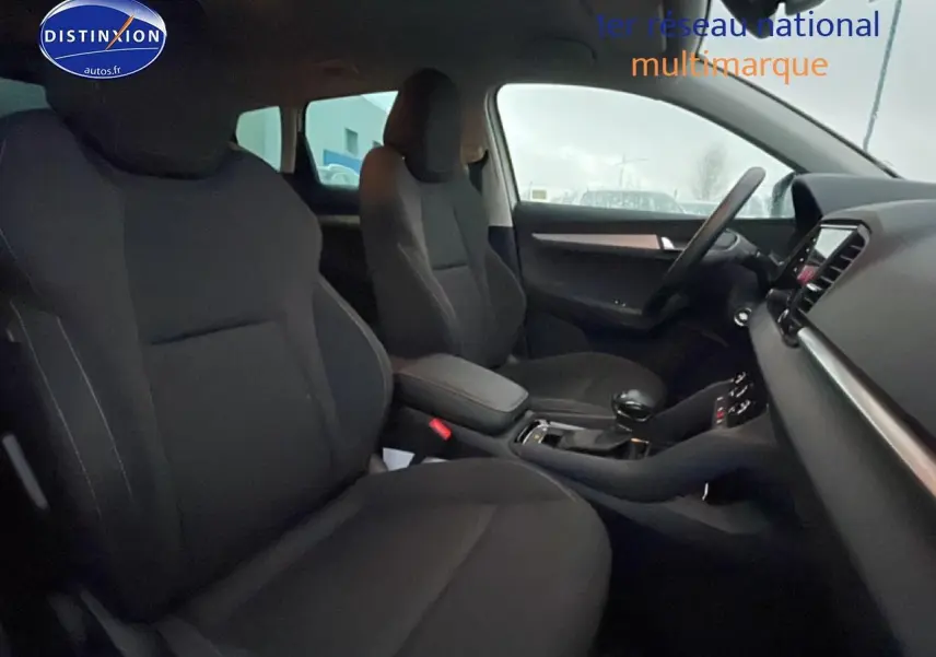 Vue intérieure côté avant droit du Skoda Karoq blanc glacial, montrant sièges noirs et console centrale avec boîte auto.