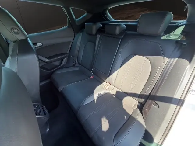 Vue intérieure de la banquette arrière en cuir noir du CUPRA Formentor blanc, avec appuie-têtes et ceinture de sécurité visibles.