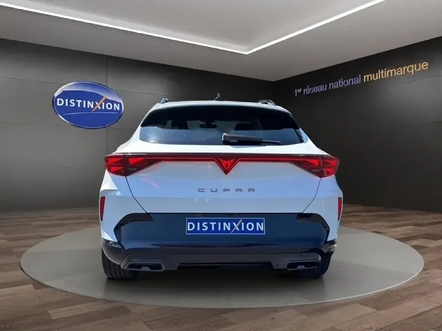 Vue arrière d'une CUPRA Formentor blanche 2025 avec feux LED distinctifs et logo rouge, en intérieur showroom.