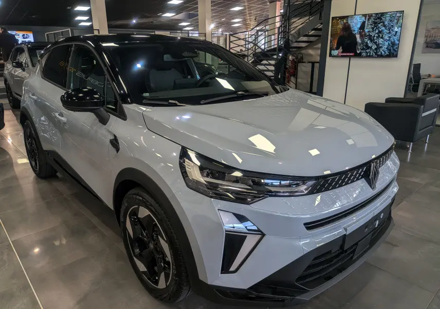 Renault Captur Mild Hybrid gris Rafale avec toit noir, vue 3/4 avant droit en showroom lumineux.