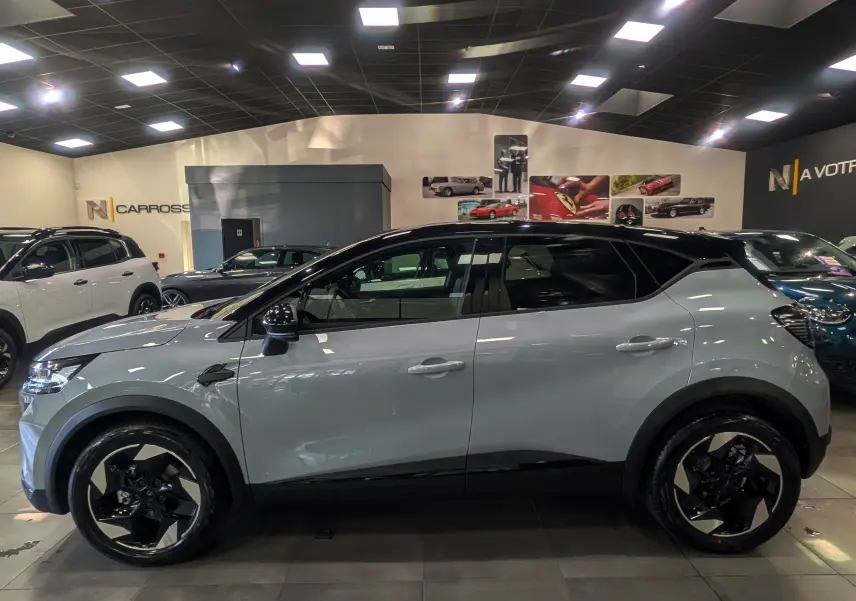 Profil latéral droit du Renault Captur 2025 gris Rafale avec toit noir et jantes bicolores en concession.