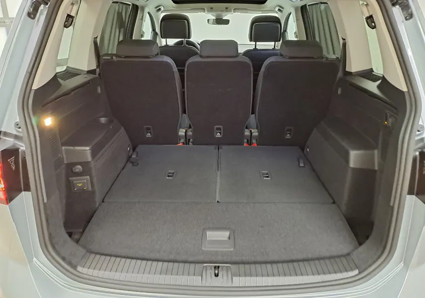 Coffre ouvert du Volkswagen Touran gris argent 2025, vue arrière montrant sièges arrière et espace de chargement modulable.