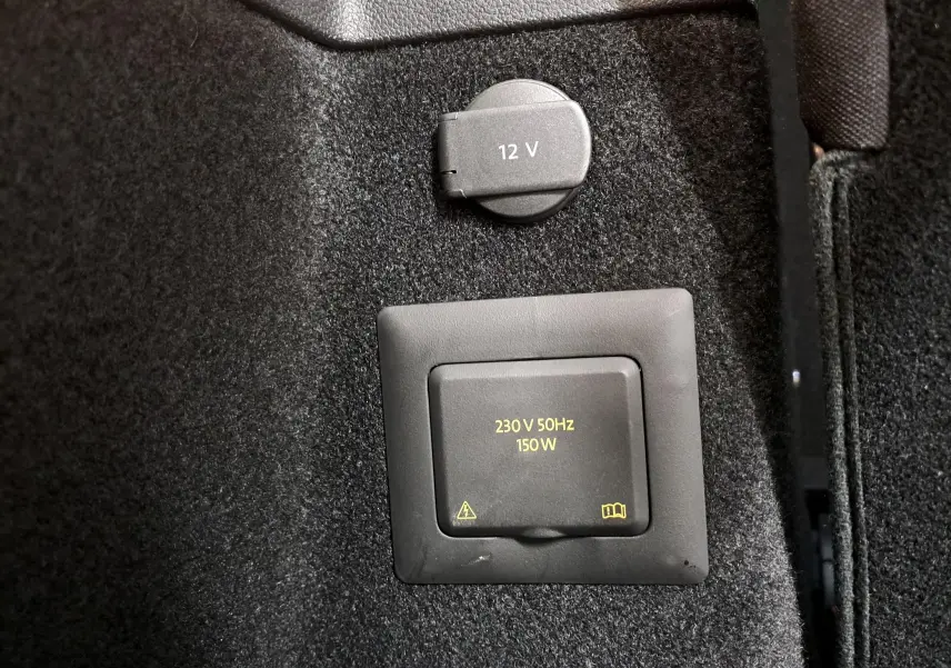 Prise 230 V et prise 12 V intégrées dans le coffre du Volkswagen Touran gris argent 2025, vue rapprochée.