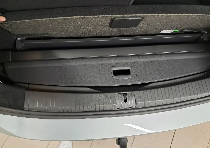 Vue plongeante sur le coffre ouvert du Volkswagen Touran gris argent, montrant la plage arrière et le seuil de chargement.