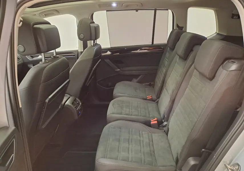 Vue intérieure côté droit des sièges arrière en tissu gris foncé du Volkswagen Touran 2025 avec habillage noir et stores pare-soleil.