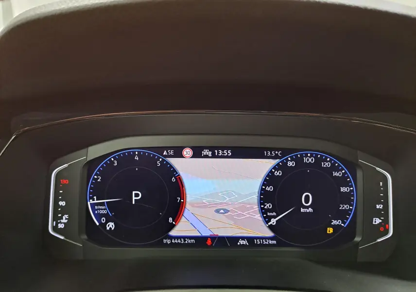Vue rapprochée du tableau de bord numérique du Volkswagen Touran gris argent, affichant la navigation et les compteurs.