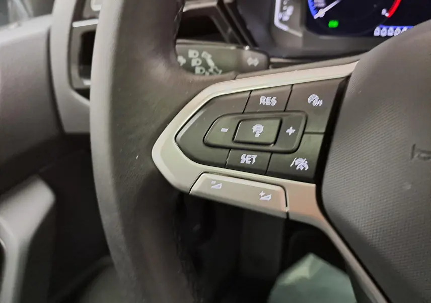 Gros plan sur les commandes au volant à gauche du Volkswagen Touran 2025, soulignant les boutons du régulateur et assistant de conduite.