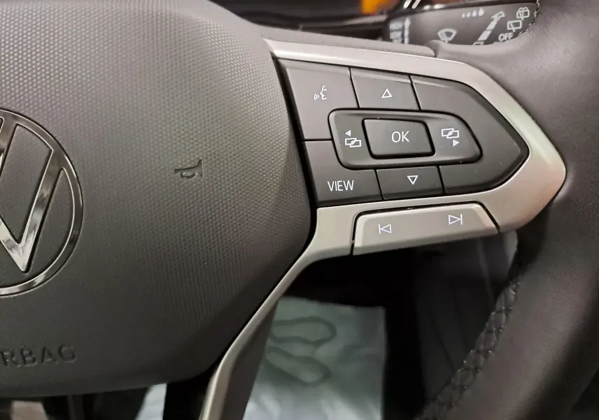 Gros plan sur les commandes multifonctions à droite du volant noir d’un Volkswagen Touran 2025.