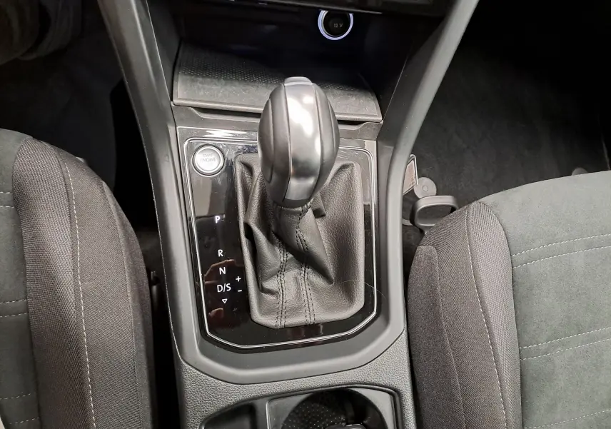 Gros plan sur le levier de vitesse automatique noir et la console centrale entre les sièges avant gris foncé du Volkswagen Touran 2025.