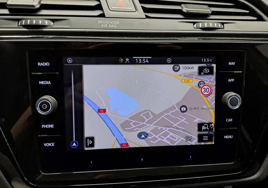 Écran tactile central du Volkswagen Touran 2025 affichant la navigation avec commandes autour en noir brillant.