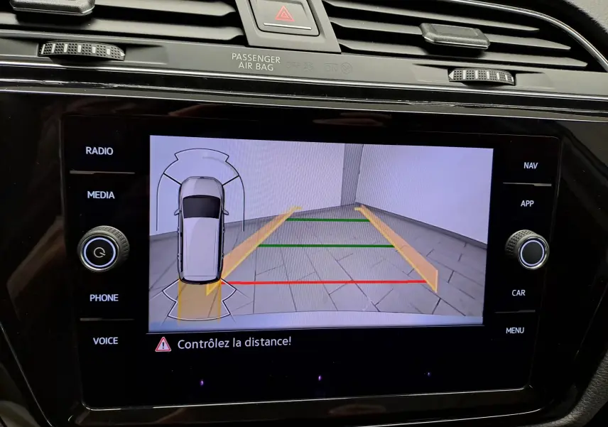Écran de caméra de recul du Volkswagen Touran gris argent montrant les lignes de guidage et l'alerte de distance.
