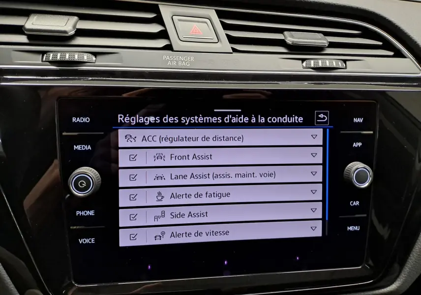 Écran tactile central du Volkswagen Touran 2025 affichant les réglages des aides à la conduite, avec commandes autour.