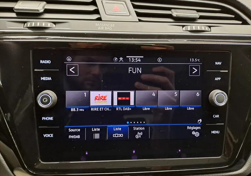 Écran tactile central du Volkswagen Touran 2025 affichant la radio numérique FM/DAB avec commandes autour et ventilation au-dessus.