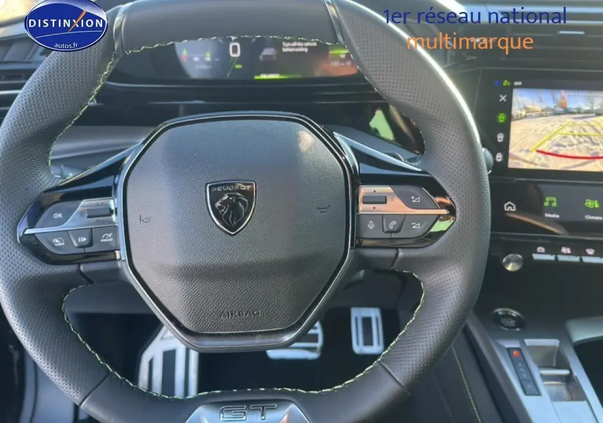 Vue rapprochée du volant cuir noir avec logo Peugeot et tableau de bord numérique de la 408 Hybrid 145 GT.