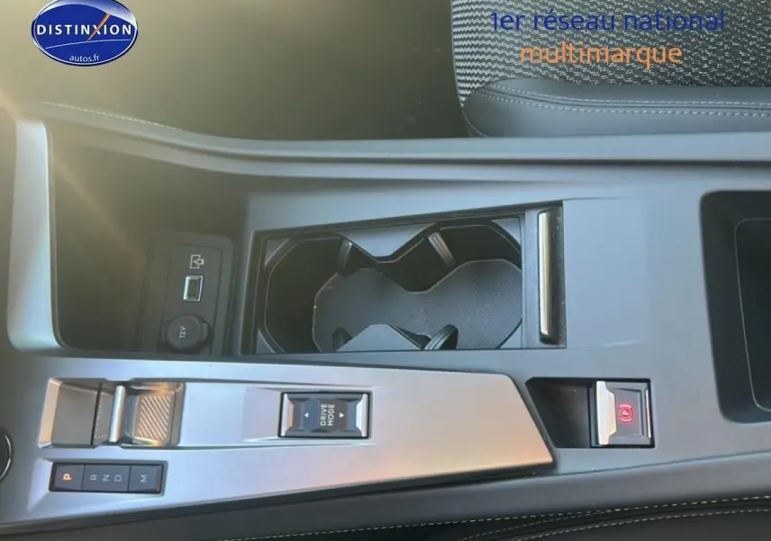 Vue plongeante sur la console centrale noire du Peugeot 408 Hybrid 145 GT avec commandes de boîte auto et porte-gobelets.