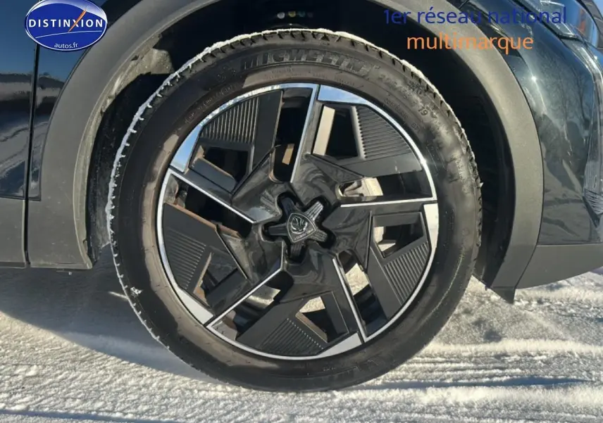 Gros plan sur la jante alu noire et argentée du côté avant droit d'une Peugeot 408 Hybrid 145 GT noir.