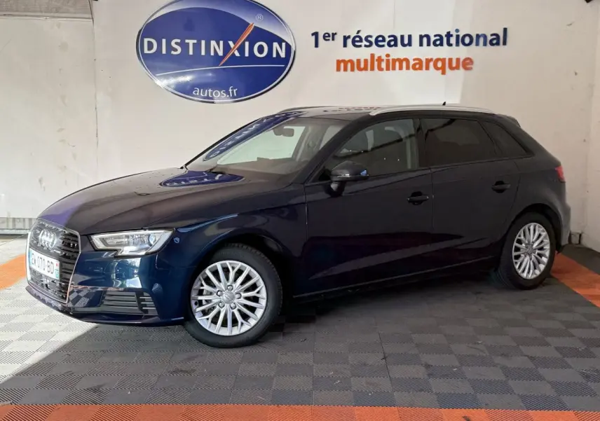 Audi A3 2.0 TDI bleu vue de profil côté gauche dans un showroom avec logo Distinxion en arrière-plan.