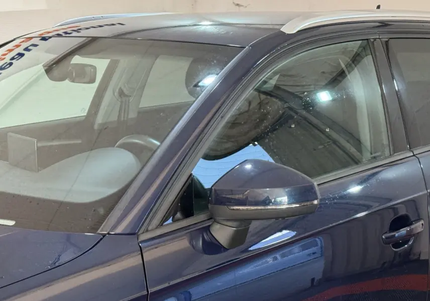 Vue rapprochée côté gauche d’une Audi A3 2.0 TDI Business Line bleu avec rétroviseur et portière visibles.