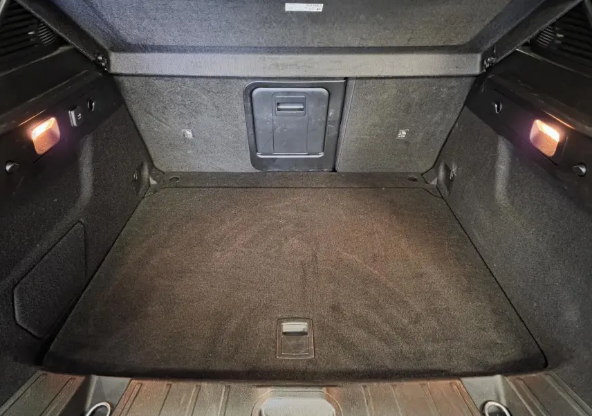 Coffre spacieux de l'Alfa Romeo Tonale 2025, vue intérieure arrière avec éclairage et revêtement noir.