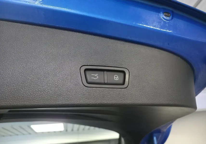 Détail du hayon électrique bleu de l'Alfa Romeo Tonale 2025 avec bouton de fermeture mains libres et verrouillage intégré.