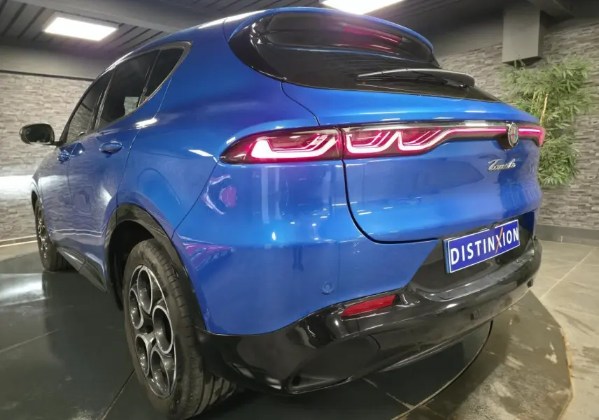 Vue 3/4 arrière gauche d'une Alfa Romeo Tonale bleue avec feux arrière LED et jantes alliage 18 pouces noires.