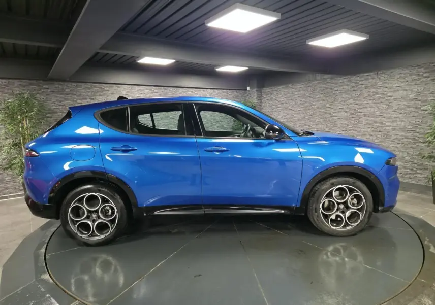 Profil côté gauche d'un Alfa Romeo Tonale bleu métallisé 2025 avec jantes alliage 18 pouces et rétroviseurs noirs brillants.