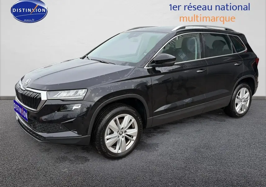 Vue 3/4 avant d’un Skoda Karoq noir 2025 avec jantes alu et barres de toit visibles sur fond neutre.