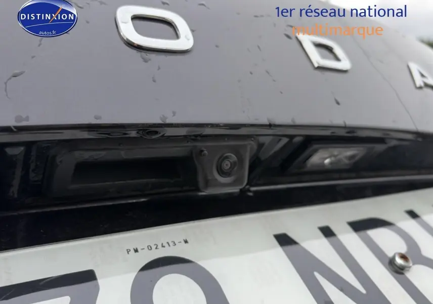 Gros plan sur la caméra de recul intégrée au hayon noir d'un Skoda Karoq 2025, avec logo partiel visible.