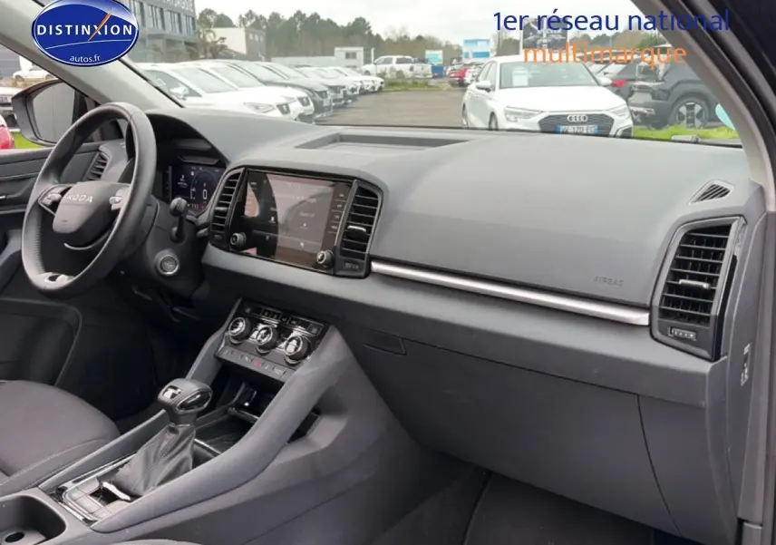Vue intérieure côté passager du Skoda Karoq noir 2025, montrant tableau de bord et console centrale moderne.