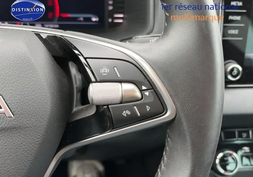 Gros plan sur le volant cuir noir du Skoda Karoq 2025 avec commandes multifonctions et écran tactile en arrière-plan.