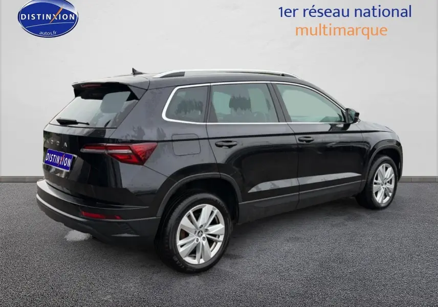 SUV Skoda Karoq noir vu de trois quarts arrière droit, avec jantes alu et barres de toit visibles.