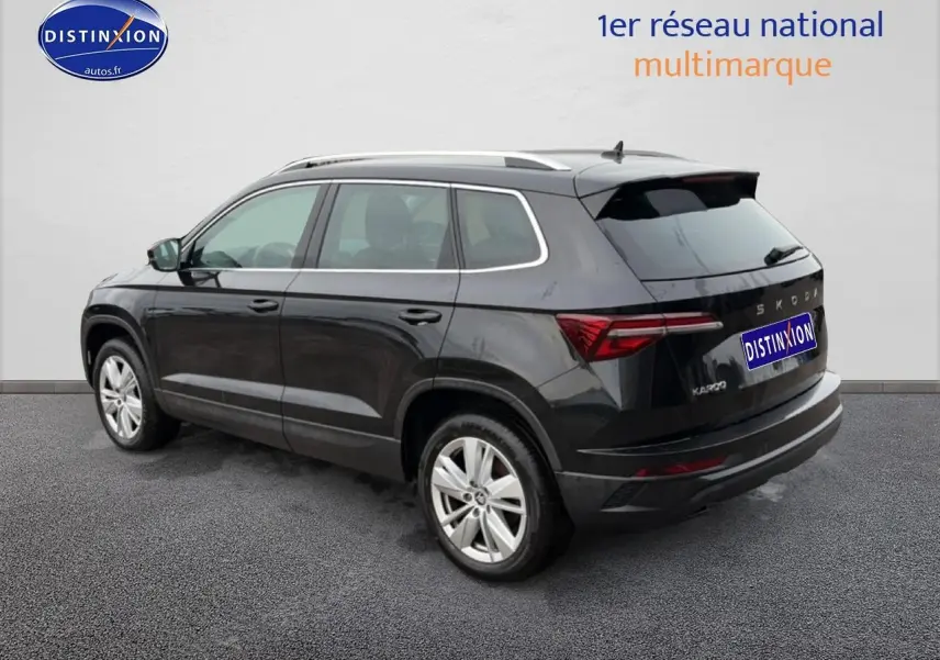 Vue 3/4 arrière droite d'un Skoda Karoq noir 2025 avec barres de toit et feux arrière LED distinctifs.