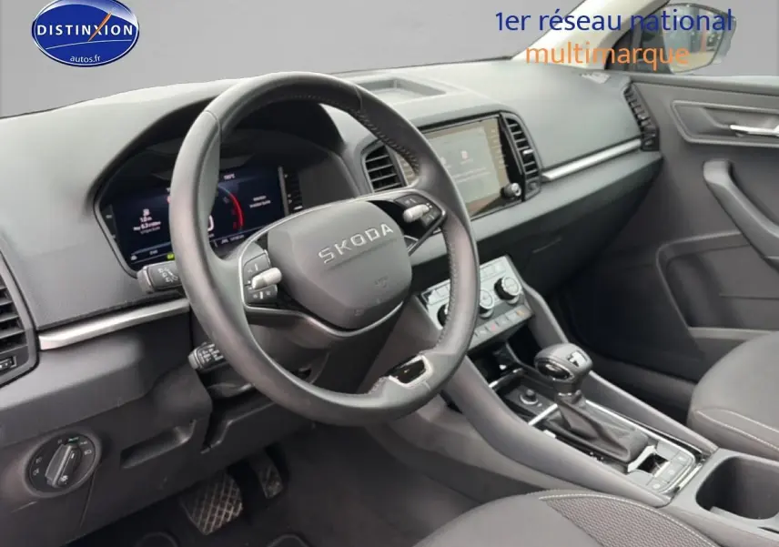 Vue intérieure du poste de conduite du Skoda Karoq noir 2025, volant cuir multifonction et écran tactile central visible.