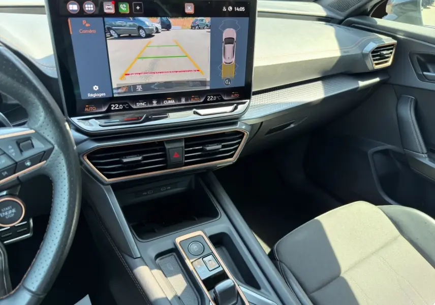 Vue intérieure côté conducteur du tableau de bord et écran tactile affichant la caméra de recul du CUPRA Formentor gris foncé.